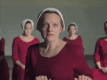 a woman in a red dress is standing in front of a group of women in red dresses