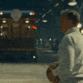 a man in a white jacket is standing in front of a train and a basketball hoop