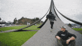 a man in a black hoodie with the word danger on it sits in front of a large sculpture