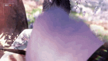 a video of a person sitting under a tree with flowers on it