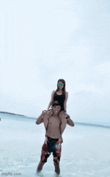 a man is carrying a woman on his shoulders in the water at the beach