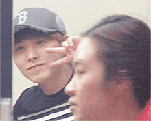 a man wearing a hat with the letter b on it is making a peace sign