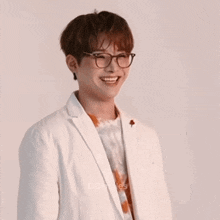 a man wearing glasses and a white jacket smiles