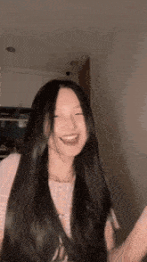 a woman with long black hair is smiling and dancing in a kitchen .