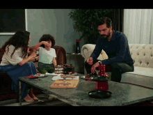 a man and a woman sit on a couch while a little boy sits at a table with a cake on it