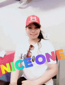 a woman wearing a hat and a white shirt with the word nice one on it