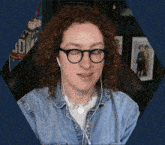 a woman with curly hair wearing glasses and earbuds looks at the camera