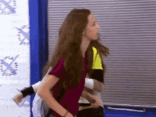 a woman with long brown hair is standing in a room with a blue door .