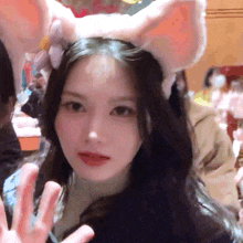 a close up of a woman wearing bunny ears and waving