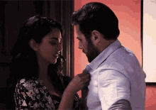 a woman adjusts a man 's tie while they are kissing