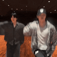 two men are dancing in a dark room and one of them is wearing a hat that says u.n.f.c.
