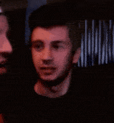 two men are standing next to each other in a dark room .