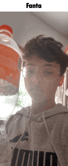 a young boy holding a bottle of fanta in front of his face