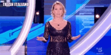 a woman in a black dress is standing on a stage with her hands outstretched and a sign that says trash italiano .