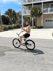a shirtless man rides a bike down a street