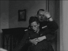 a man in a military uniform is holding another man in his arms .