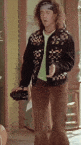 a man with curly hair wearing a headband and a jacket with buttons on it
