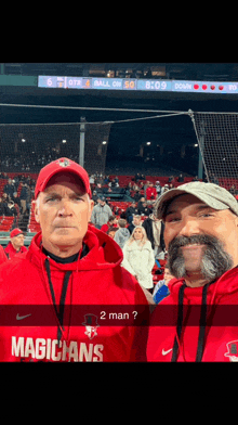 a man wearing a red magicians sweatshirt stands with another man