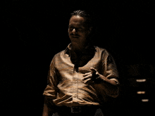 a man with a tattoo on his arm is wearing a brown shirt
