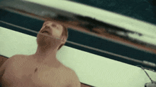 a shirtless man is laying on a boat looking up at the sky