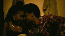 a man in a plaid shirt looks at a woman in a black tank top