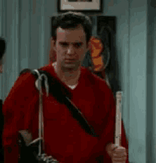 a man in a red sweater is holding a cane and a backpack .