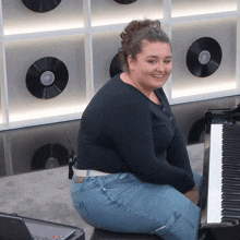 a woman sits in front of a piano with records on the wall