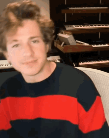a man wearing a red and black striped sweater is sitting in front of a keyboard