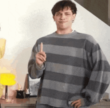 a young man wearing a striped sweater is holding a banana and pointing up .