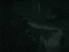 a shirtless man in a dark room holding a sword
