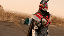 a man in a costume with a helmet and a cape is standing on a road