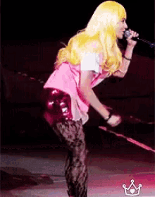 a woman with blonde hair is singing into a microphone on stage