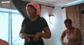 two women are standing in a room with a sign that says nowthis tv on it