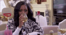 a woman is drinking a glass of white wine while sitting at a table .