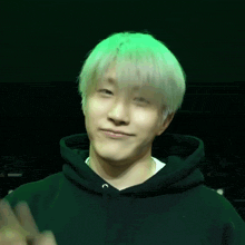 a man with white hair wearing a black hoodie