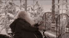 a man with a long beard is sitting on a bench in the snow
