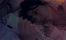 a woman is laying in bed holding a colorful object in her mouth .