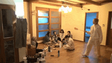 a group of people are sitting on the floor in a living room with a man holding a spatula