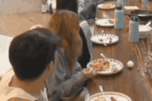 a group of people are sitting at a table eating food .