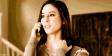 a woman is talking on a cell phone while standing in front of stairs .