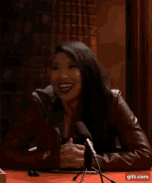 a woman sitting in front of a microphone smiling