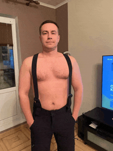 a shirtless man wearing suspenders stands in front of a television screen that says ox