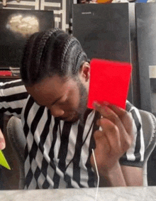 a man in a striped shirt is holding a red card in his hands .