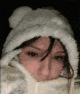 a woman wearing a white furry hat and a white scarf covering her face .