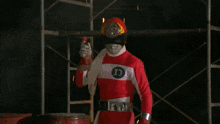 a man in a red and white superhero costume is holding a large gold shield