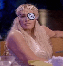 a woman wearing a headband and a patch on her eye is sitting at a table .