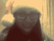 a woman wearing a santa hat and glasses looks at the camera