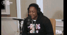 a man wearing headphones is sitting in front of a microphone with new amsterdam vodka written on the wall behind him