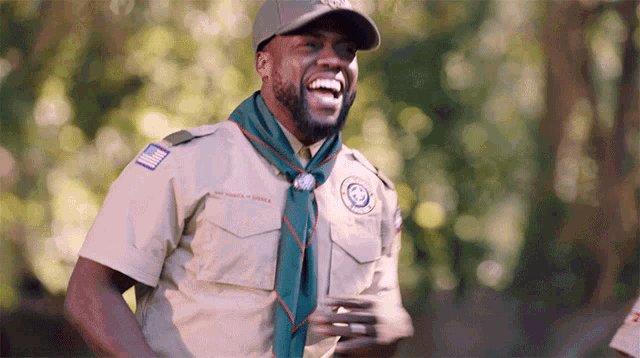 a man in a boy scout uniform is laughing and wearing a hat with a patch that says united states of america