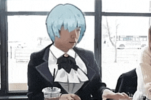 a man in a suit and tie is sitting at a table with a cup of coffee .